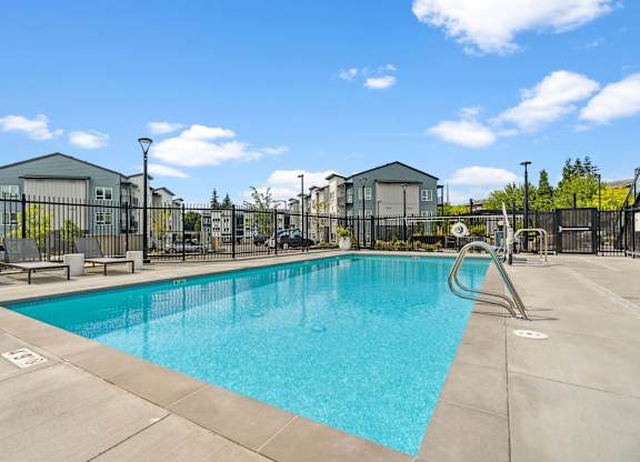 A large swimming pool surrounded by a fence and buildings.
