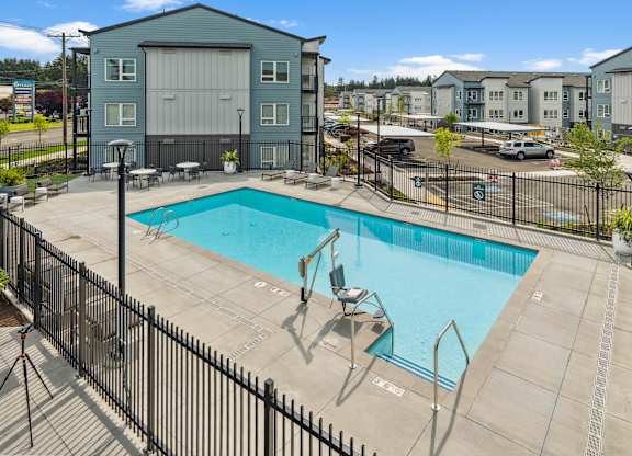 A pool surrounded by a black fence with a building in the background.