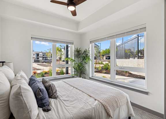 A bedroom with a bed, pillows, and a ceiling fan.