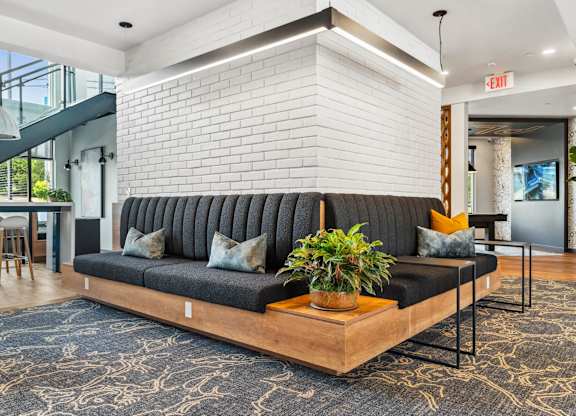 A black couch with a wooden table in front of a white brick wall.