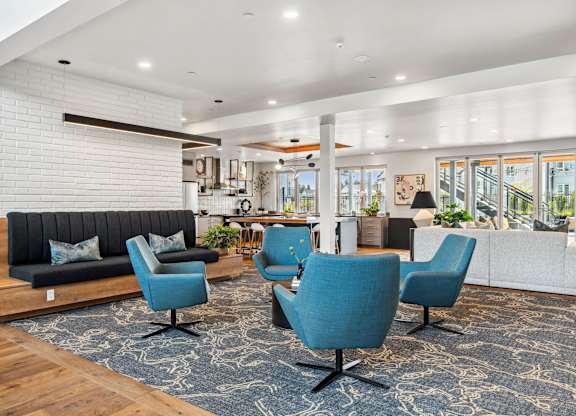 A modern living room with a black sofa, blue chairs, and a wooden floor.