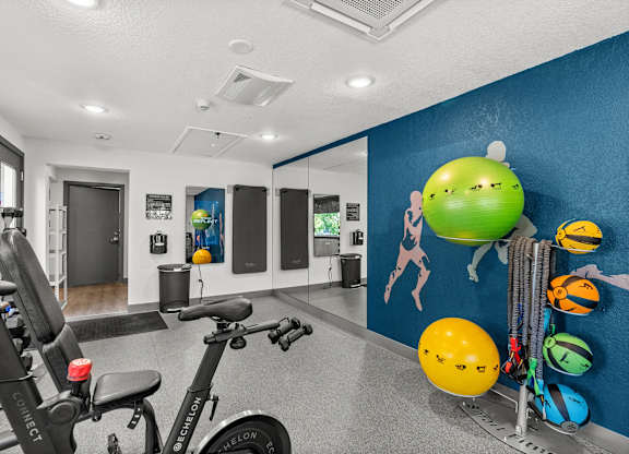 A gym room with exercise equipment and a blue wall with drawings of lemons.