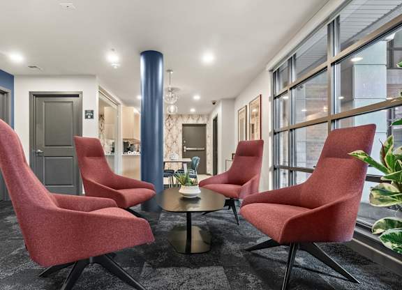 A room with red chairs and a round table.