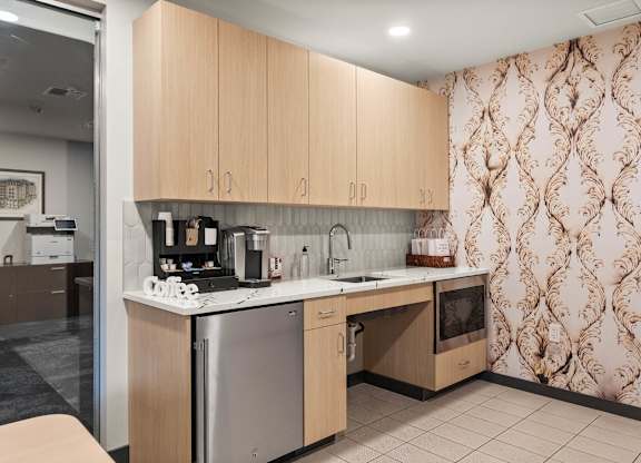 A kitchen with wooden cabinets and a patterned wallpaper.
