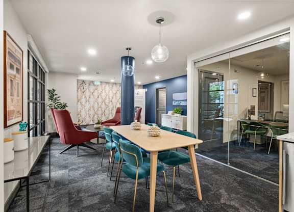A dining room with a table surrounded by chairs.