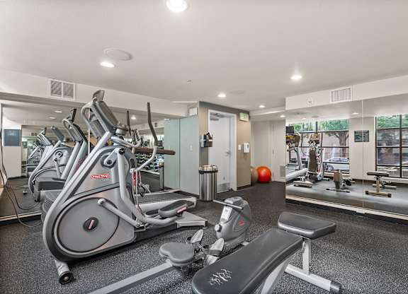 A gym with a variety of equipment including treadmills, stationary bikes, and weight machines.