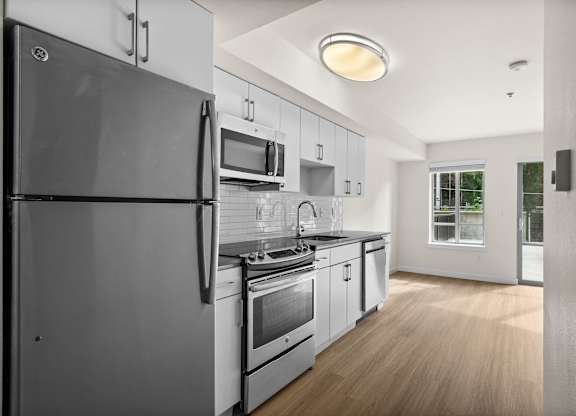 A modern kitchen with a refrigerator, microwave, oven, and sink.