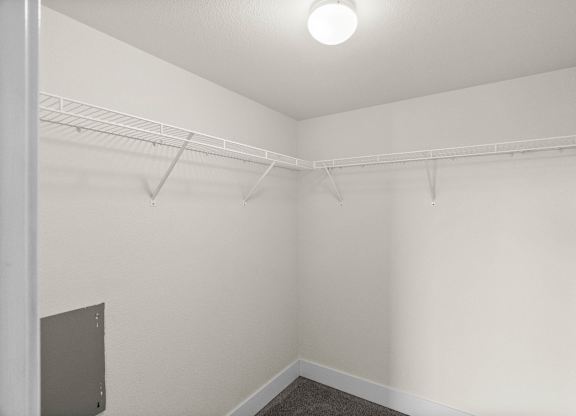 A white room with a shelf and a light on the ceiling.