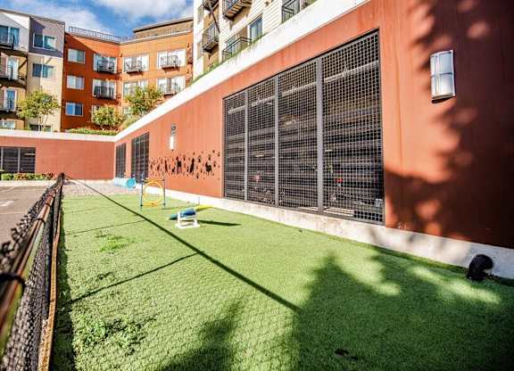 A small grassy area in front of a building with a fence on the left side. at The Platform, Washington, 98032