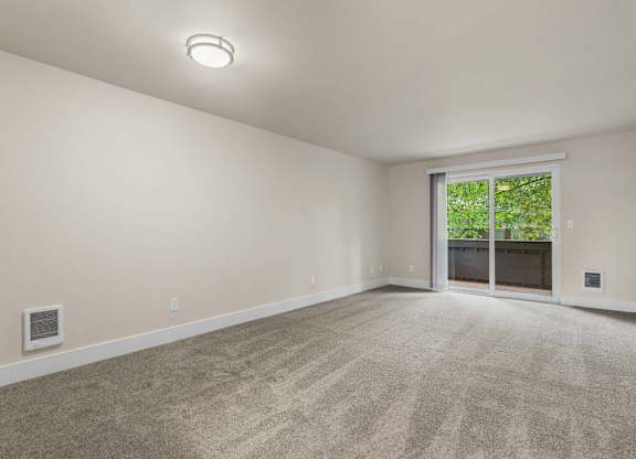 an empty living room with a large window and carpeting at Bellamy Park Apartments , Washington