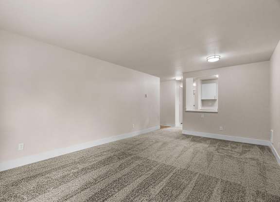 an empty living room with carpet and white walls at Bellamy Park Apartments , Lakewood