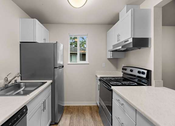 an empty kitchen with white cabinets and stainless steel appliances at Bellamy Park Apartments , Lakewood, CA