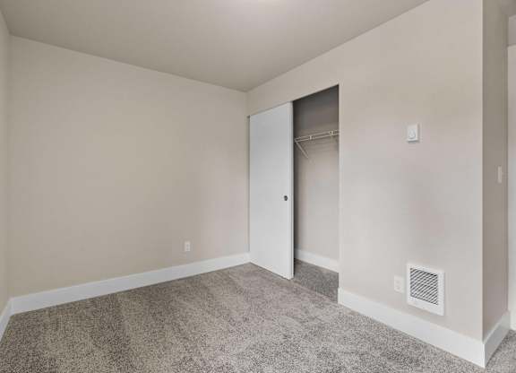 an empty bedroom with a closet and a carpeted floor at Bellamy Park Apartments , Lakewood, CA, 98498