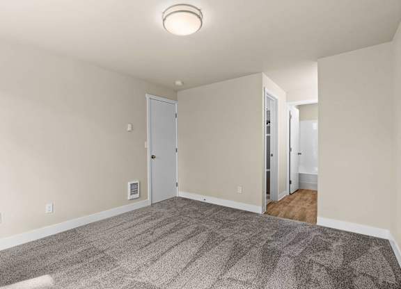 an empty living room with carpet and white walls at Bellamy Park Apartments , Lakewood