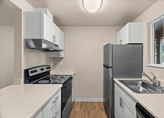 a kitchen with white cabinets and black appliances and a stainless steel refrigerator at Bellamy Park Apartments , Lakewood, Washington