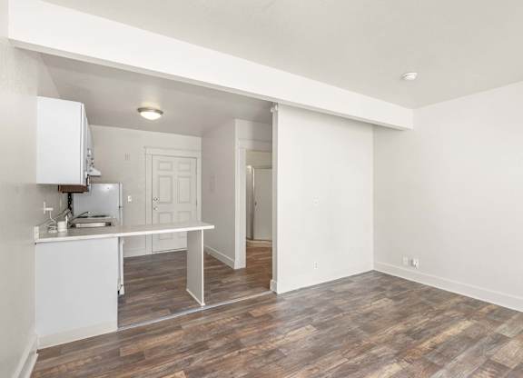 A kitchen with white cabinets and a wooden floor.
