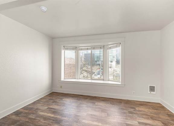 A room with a window and wooden flooring.