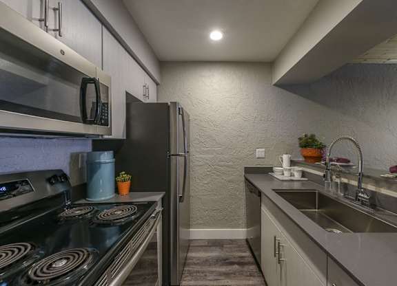 A modern kitchen with a stove, refrigerator, and sink.