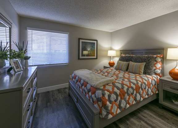 A bedroom with a bed, nightstand, and a painting on the wall.