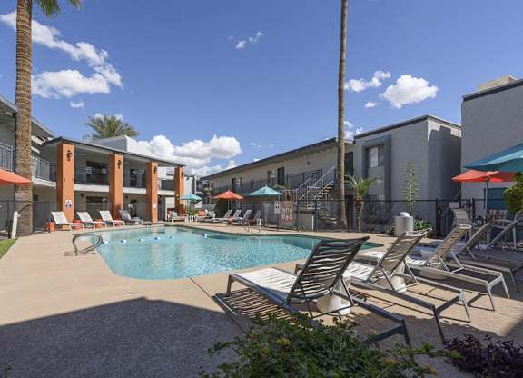 A pool surrounded by lounge chairs and umbrellas.