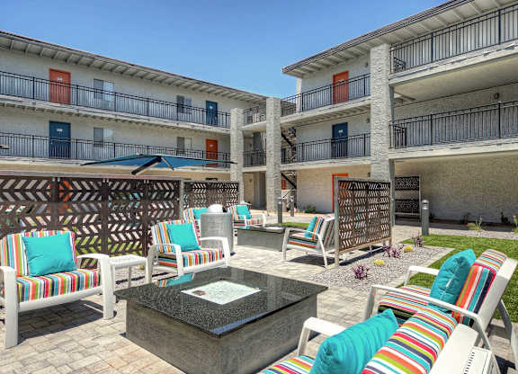 A patio area with a table and chairs in front of apartment buildings.