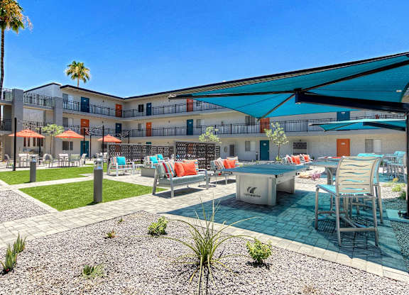 A pool area with a table and chairs under a shade sail.