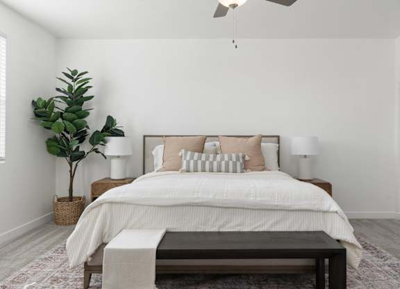 A bedroom with a large bed, a plant, and a ceiling fan.