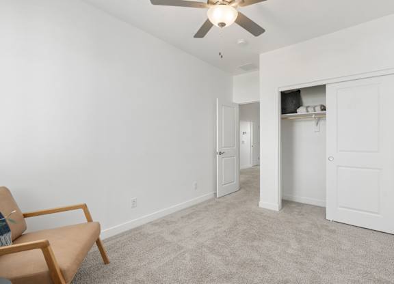 A room with a ceiling fan and a chair.