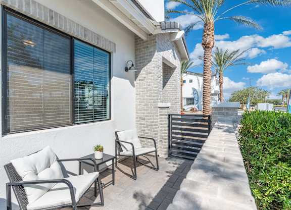 A patio with a table and chairs is in front of a house.