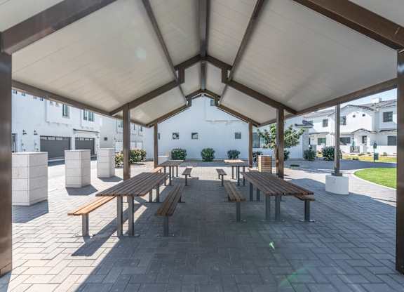 A covered outdoor seating area with benches and tables.
