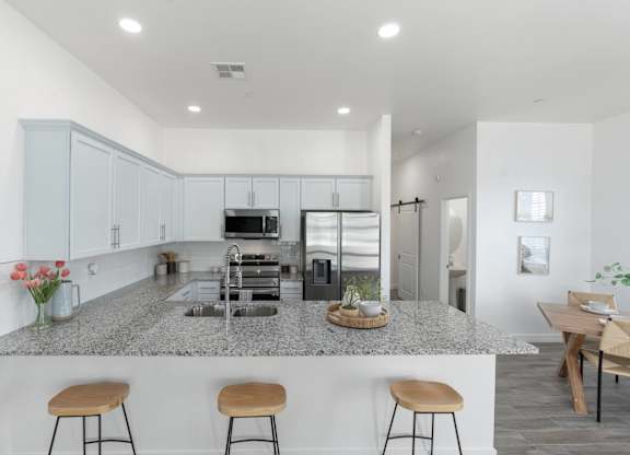 A kitchen with a granite countertop and stools.