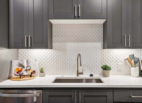A kitchen with a white countertop and a white tile backsplash.