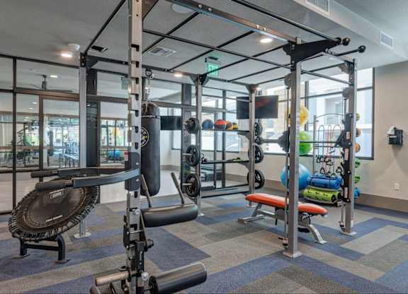 A gym with a variety of equipment including a weight bench, a rowing machine, and a treadmill.