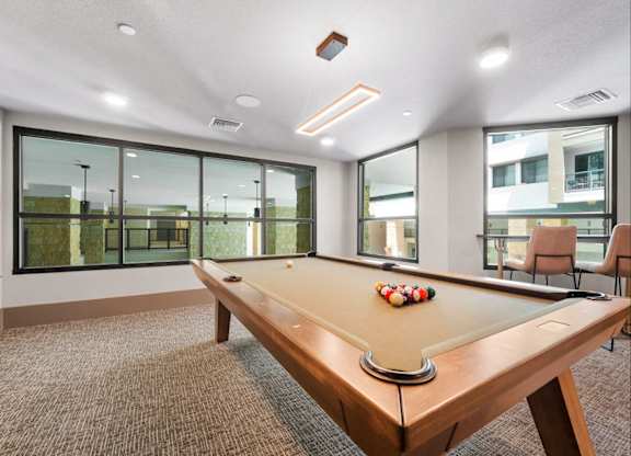 A pool table in a room with a brown carpet.