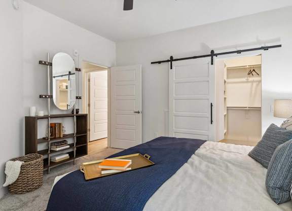 A bedroom with a bed, a dresser, a mirror, and a bookshelf.