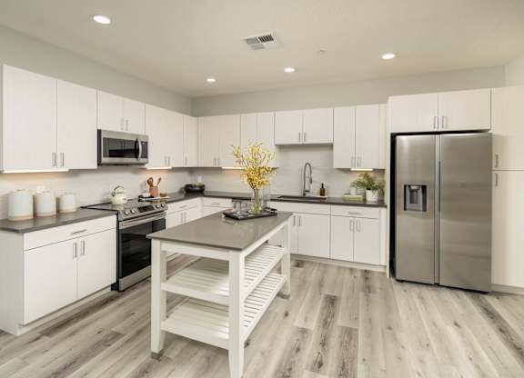 A modern kitchen with white cabinets and a wooden island.