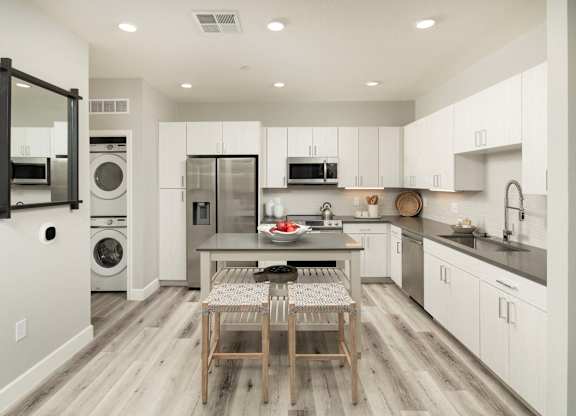 A modern kitchen with a dining table and chairs in the middle.