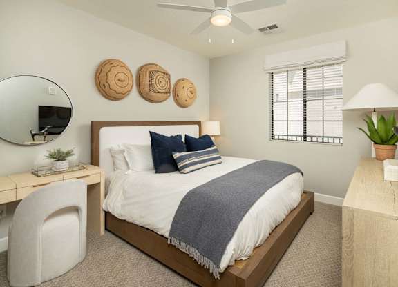 A bedroom with a bed, desk, chair, and a mirror.