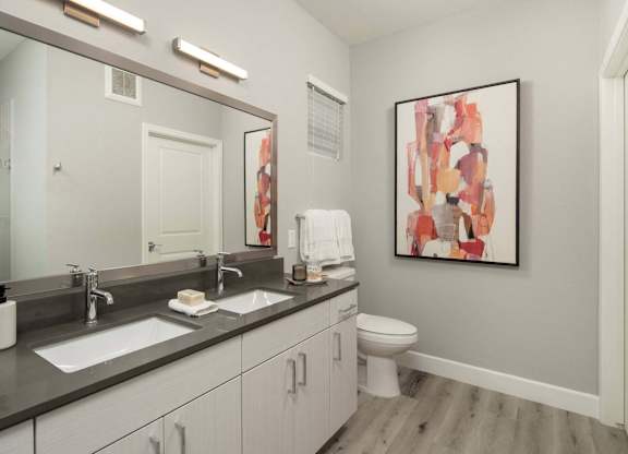A bathroom with a large mirror, a sink, a toilet, and a painting on the wall.
