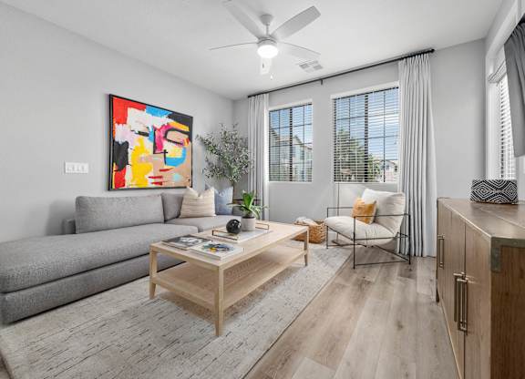 A living room with a grey sofa, a wooden coffee table, and a painting on the wall.