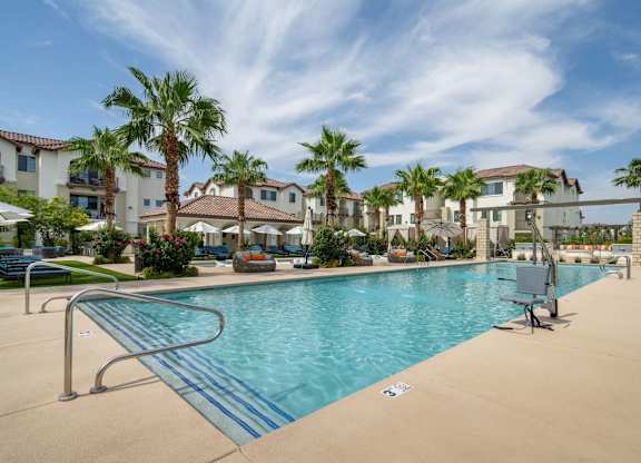 A swimming pool surrounded by palm trees and a building in the background.