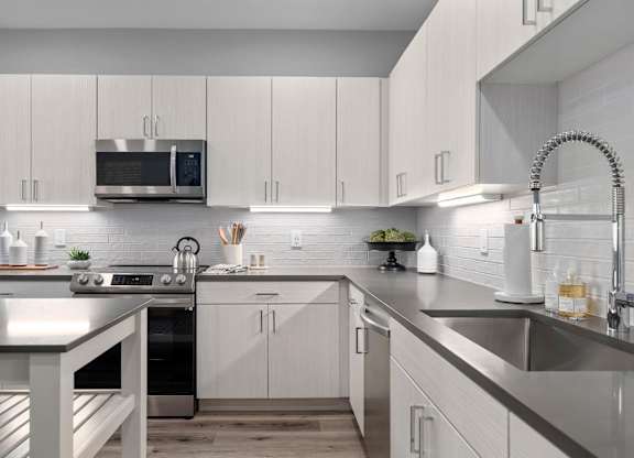 A modern kitchen with white cabinets and stainless steel appliances.