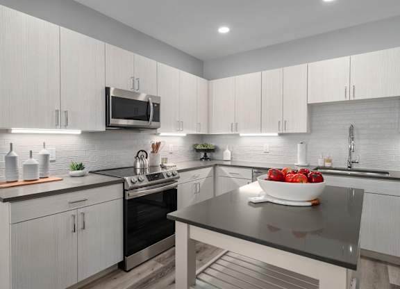 A modern kitchen with a black countertop and white cabinets.