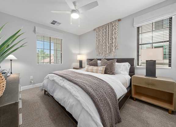 A bedroom with a large bed and a ceiling fan.