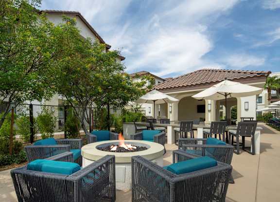 A patio with a fire pit and chairs.