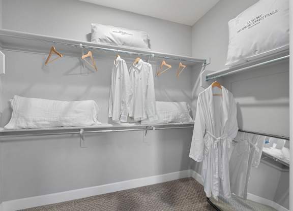 A white hotel room with two beds and towels hanging up.