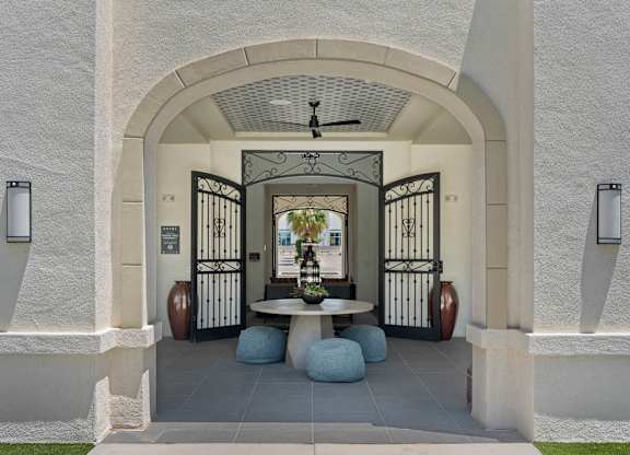 A white building with a black gate and a fan in the middle.