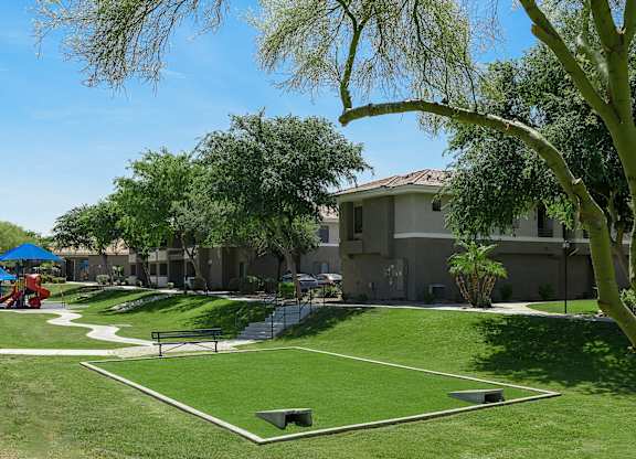 A park with a playground and a building in the background.