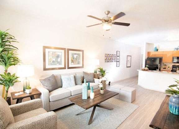 A living room with a couch, a coffee table, and a ceiling fan.
