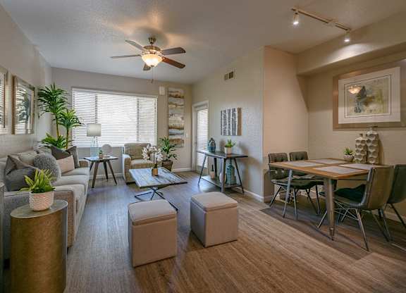 A living room with a grey couch, a wooden table, and a ceiling fan.